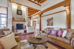 A spacious living room with leather sofas, a coffee table, and wooden beams on the ceiling.