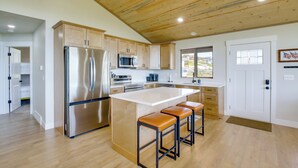 Una cocina moderna con techo de madera, electrodomésticos de acero inoxidable y una isla grande con taburetes de bar.