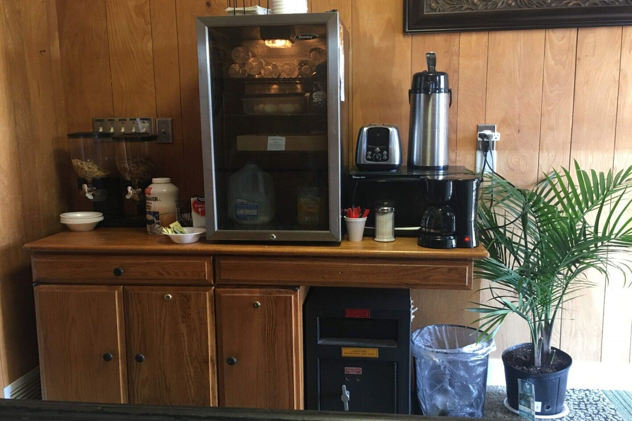 A kitchenette with a refrigerator, coffee maker, and a potted plant.