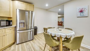 Una cocina con electrodomésticos de acero inoxidable, armarios de madera y un comedor con mesa y sillas.