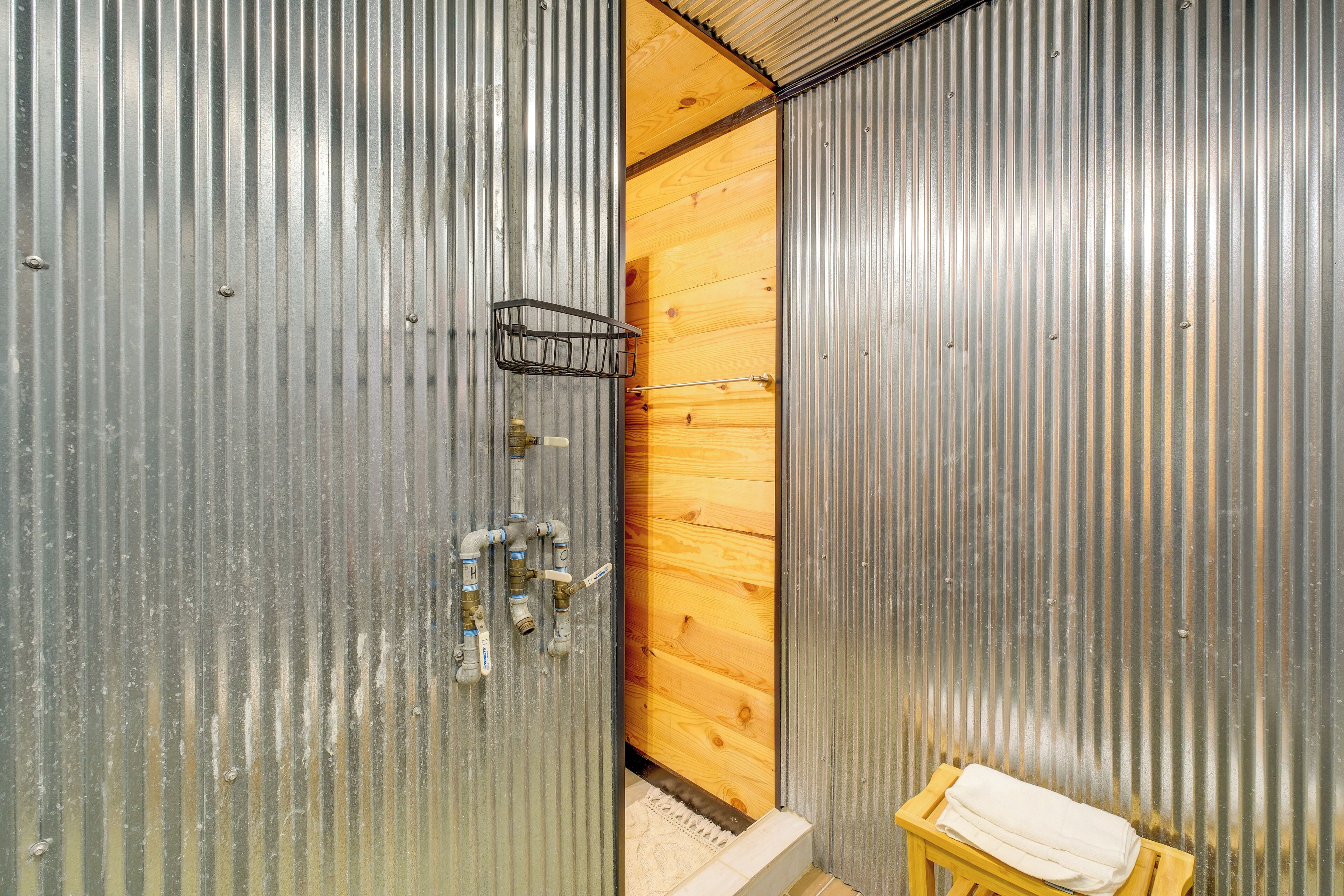 A bathroom with a wooden door, a towel rack, and a small wooden stool.