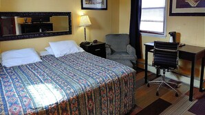 Hotellihuone, jossa on sänky, työpöytä, tuoli, lamppu ja ikkuna.