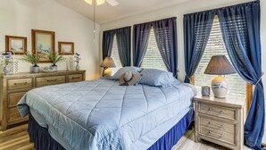 Ein Schlafzimmer mit einem Bett, Nachttischen, einem Schminktisch und einem Deckenventilator.