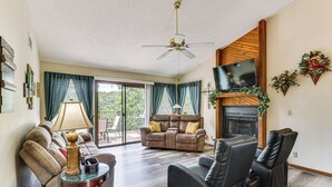 Ein Wohnzimmer mit Sofa, Liege-Sessel, Fernseher, Kamin und Deckenventilator.