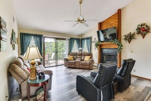 A living room with a sofa, recliner, TV, fireplace, and a ceiling fan. - Pool Access! Village of Four Seasons Family Escape (Village of Four Seasons)