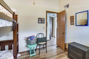 A bedroom with a bunk bed, a chair with a bag, a dresser, and a mirror on the wall.