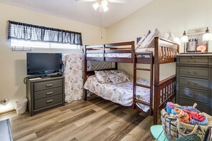 Een slaapkamer met stapelbed, televisie, dressoir en een klein tafeltje.