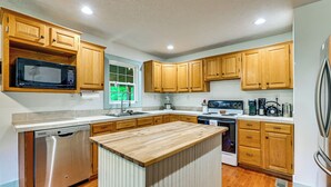 A kitchen with wooden cabinets, a built-in microwave, stainless steel dishwasher, and a central island. - Steps to Nolin Lake! Retreat 11 Mi to Mammoth Cave (Cub Run)