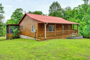 Eine Holzhütte mit rotem Dach, einer Veranda und einer kleinen Terrasse.