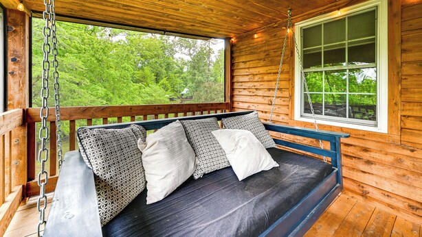A wooden cabin with a wooden deck, a swing with cushions, and a window with a view of greenery. - Steps to Nolin Lake! Retreat 11 Mi to Mammoth Cave (Cub Run)