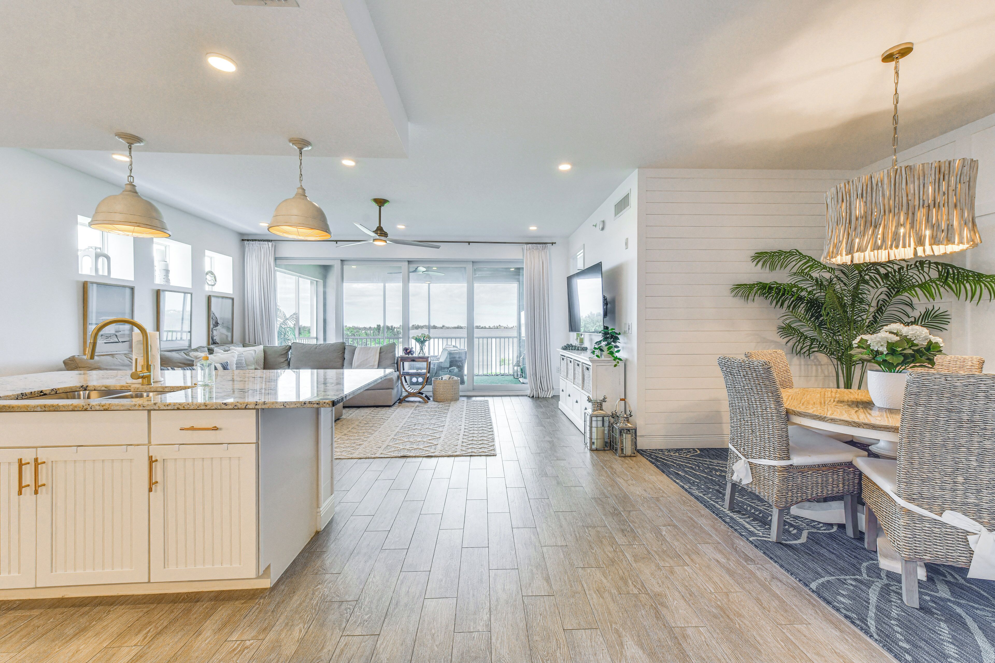 A spacious kitchen with a large island, dining area with wicker chairs, and a view to the outside.
