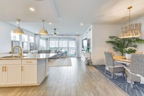 Een ruime keuken met een groot schiereiland, een eethoek met rieten stoelen en uitzicht op het omliggende landschap.