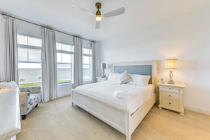 Une chambre à coucher avec un grand lit, une table de chevet, une lampe, une chaise et une vue sur l’extérieur.