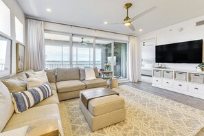 Ein geräumiges Wohnzimmer mit einem großen Sofa, einem Hocker und einem flachbildfernseher an der Wand.