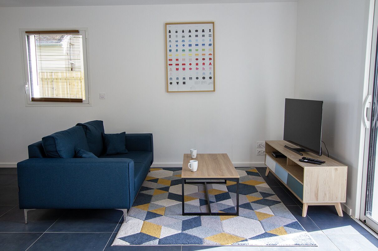 Una sala de estar con un sofá, una mesa de centro, un mueble para televisor y un tapete estampado.
