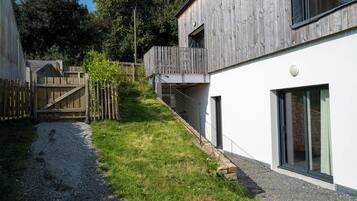 Un bâtiment moderne avec une façade en bois, un chemin de gravier et une clôture en bois.