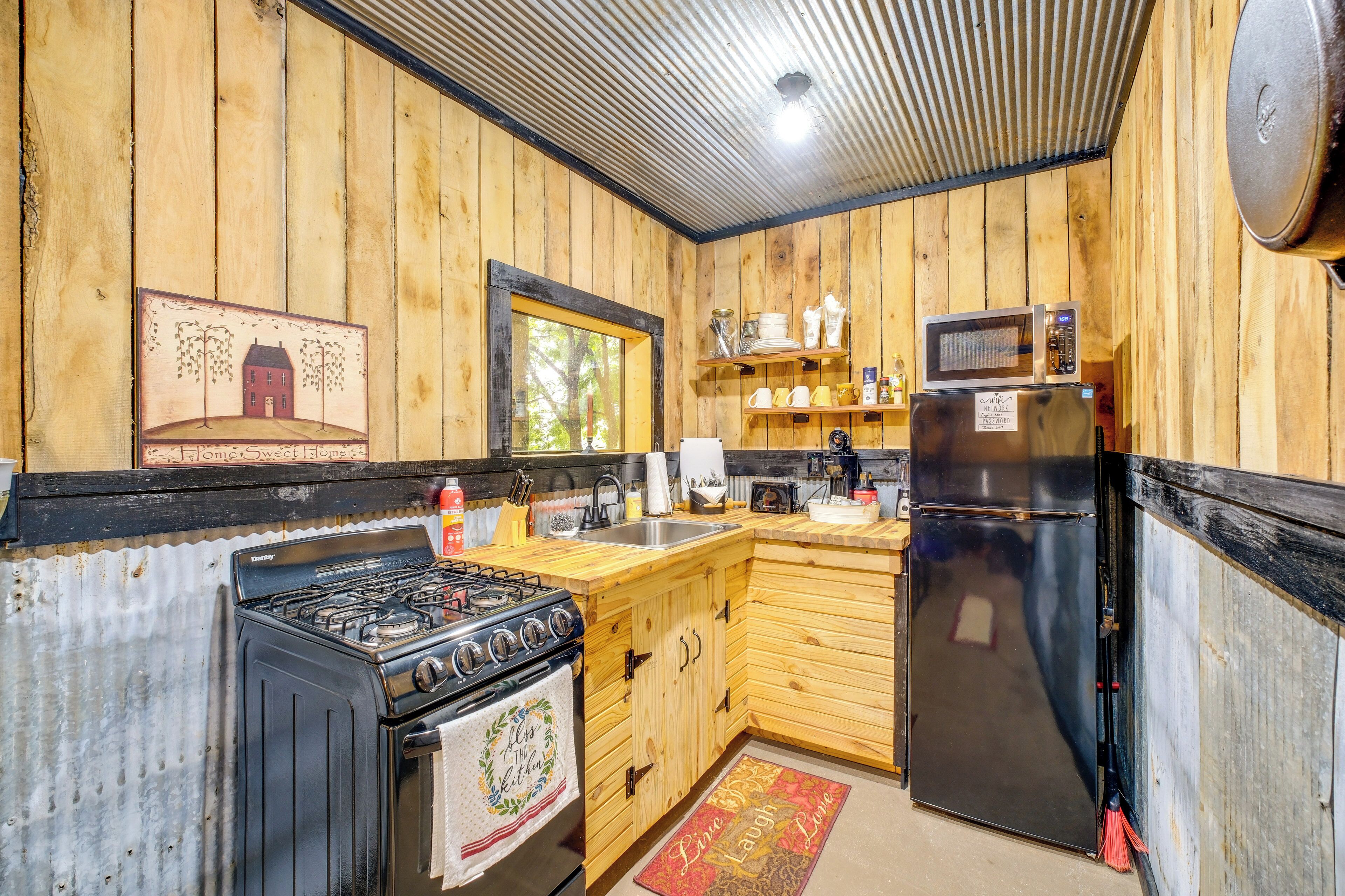 A kitchen with wooden walls, a stove, a refrigerator, and a microwave.