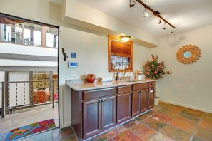 Una cocina con una isla grande, armarios de madera, una ventana con persianas y un adorno en la pared.