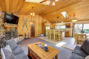Ein Holzinnenraum mit Fernseher, Kamin, Essbereich, Küche und einer Steinwand.