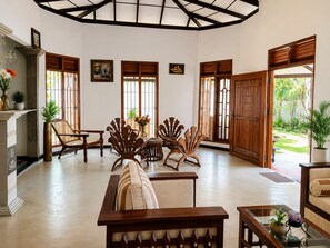 Una habitación amplia con techo alto, muebles de madera y ventanas grandes.