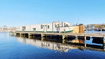 Een stilgelegen woonboot aan een steiger, met een heldere lucht.