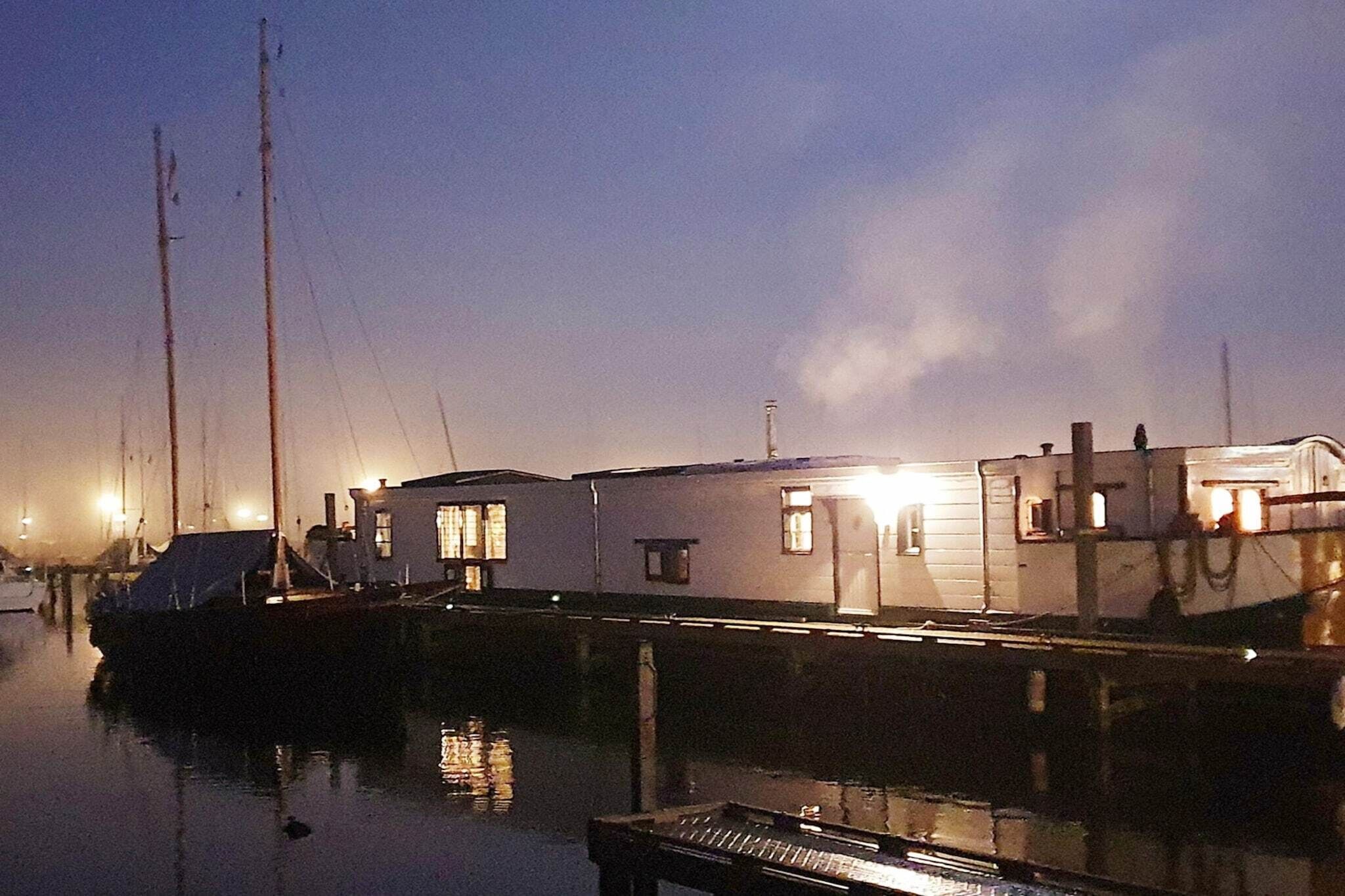Un puerto deportivo con varias embarcaciones amarradas, un edificio con ventanas y una superficie de agua tranquila.