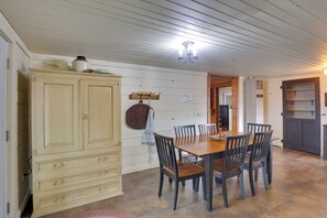 Een eetruimte met een houten tafel en stoelen, een kast in crème tinten en een plafondlamp.
