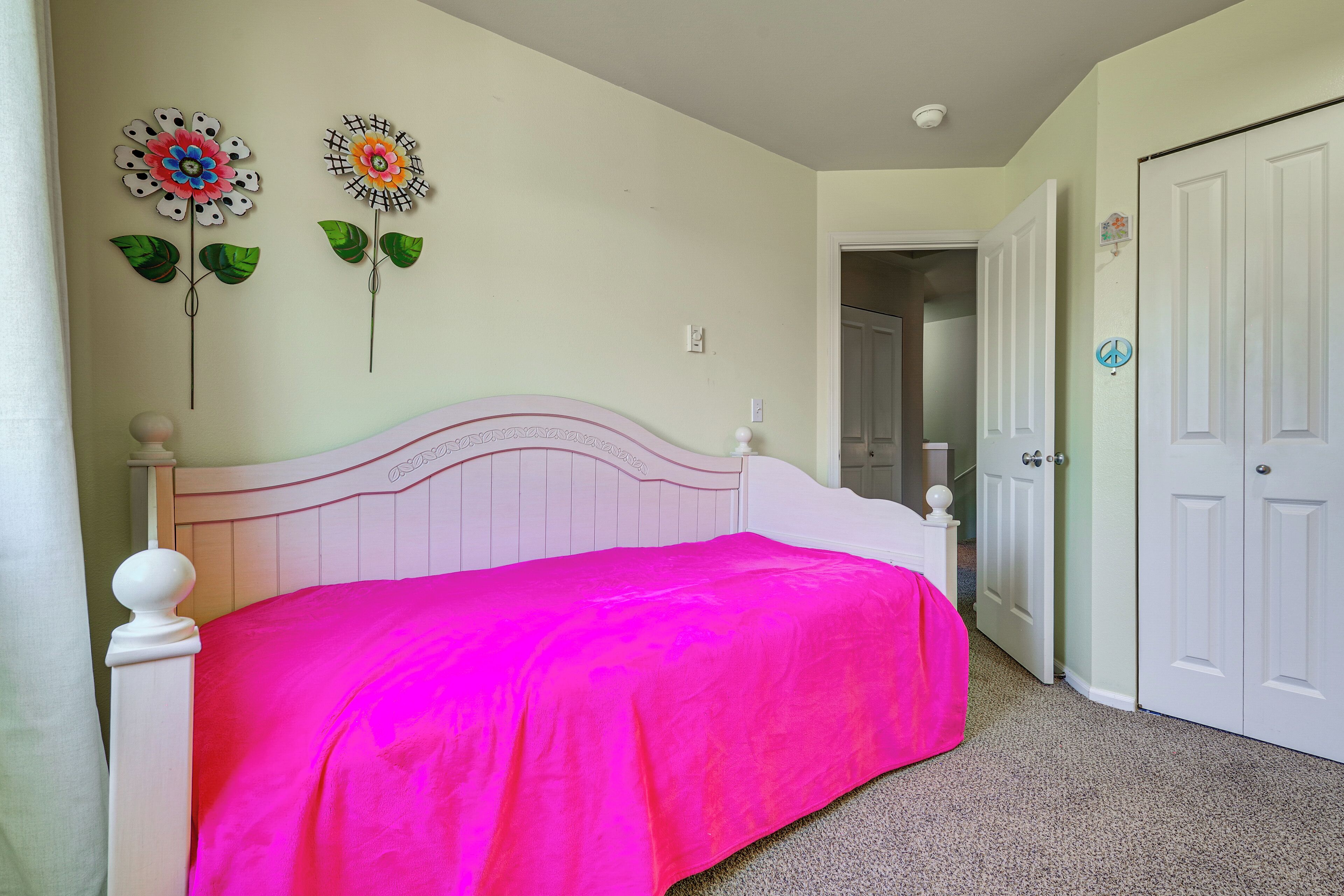 Un dormitorio con una cama, dos adornos en la pared, una puerta y un armario.