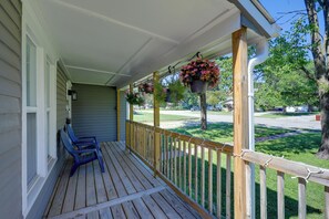 Une véranda en bois avec une balustrade, un banc et des jardinières suspendues.