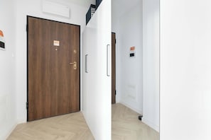Ein Flur mit einer Holztür, einer weißen Wand und einem hellen Boden.