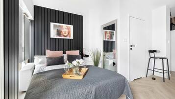 A modern bedroom with a bed, bedside tables, a mirror, and a black and white color scheme.