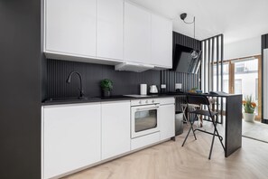 Eine moderne Küche mit weißen Schränken, einer schwarzen Arbeitsplatte, einem eingebauten Backofen und einem schwarzen Stuhl.