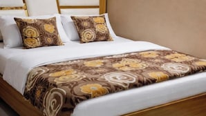 A bed with a wooden frame, white bedding, and patterned pillows. - Deva Guest House (Ayodhya)
