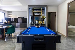 A pool table in a modern room with a kitchen in the background. - Facai Star Villa A22 (Banglamung)