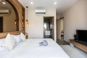 A hotel room with a large bed, a TV, a mirror, and an air conditioning unit. - Facai Star Villa A22 (Banglamung)