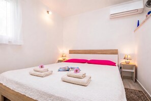 Ein Hotelzimmer mit einem Bett, zwei Nachttischlampen, einer Klimaanlage und einem Fenster mit Vorhängen.