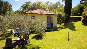 A small yellow building with a red-tiled roof, surrounded by a well-maintained lawn and trees. - Marisa Olive Grove Apartments (Labin)
