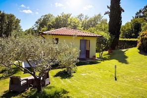 A small yellow building with a red-tiled roof, surrounded by a well-maintained lawn and trees. - Marisa Olive Grove Apartments (Labin)