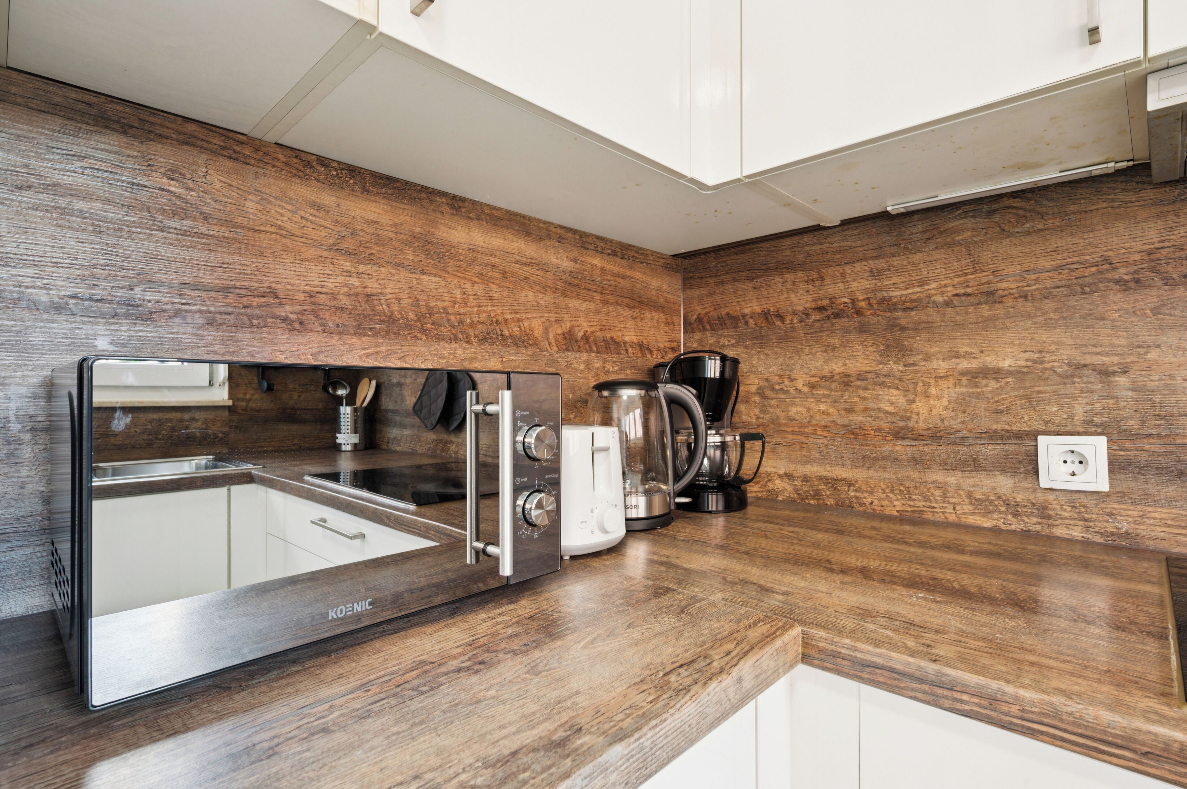 A modern kitchen with a stainless steel range hood, a coffee maker, and a toaster on a wooden countertop.