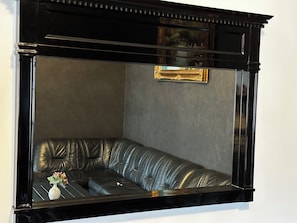 Un sofà d'angle amb estructura negra, una taula petita amb un vas i un quadre al mur.
