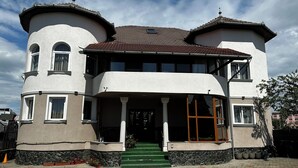 A two-story building with a curved facade, a central entrance with steps, and a tiled roof. - CROWN ROYAL APARTMENTS (Alba Iulia)