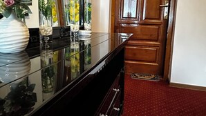 A hotel reception area with a glass display case, a wooden door, and a red carpeted floor. - CROWN ROYAL APARTMENTS (Alba Iulia)