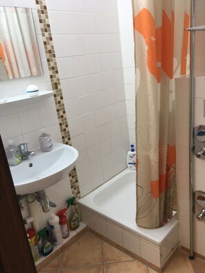 Ein Badezimmer mit Waschbecken, Spiegel, Duschvorhang und gefliesten Wänden.