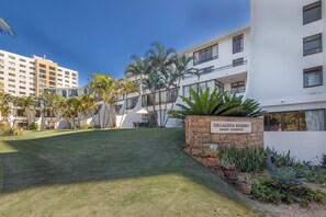 A resort with a well-maintained lawn, palm trees, and a sign indicating it's a private residence. - 211 Breakers Resort - by Stay in Umhlanga (uMhlanga)