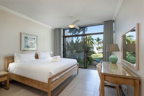 A bedroom with a bed, a desk, a chair, a ceiling fan, and a large window with a view of palm trees. - 211 Breakers Resort - by Stay in Umhlanga (uMhlanga)