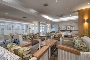 A spacious lounge area with wicker furniture, a wooden coffee table, and framed artwork on the wall. - 211 Breakers Resort - by Stay in Umhlanga (uMhlanga)