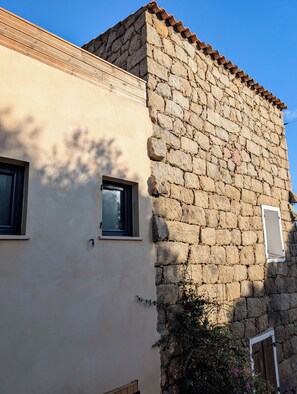 A building with a stone facade and a beige wall. - Traditional house (Figari)