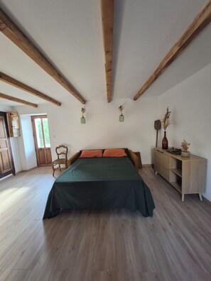 A bedroom with a bed, wooden beams, a chair, a bedside table, and a cabinet. - Traditional house (Figari)