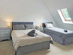 Ein Schlafzimmer mit zwei Betten, einem Oberlicht und einem Nachttisch mit Lampe.
