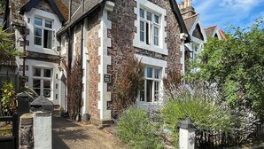 A two-story stone house with a traditional design, featuring a stone facade and white window frames. - 3 bedroom accommodation in Torquay (Torquay)